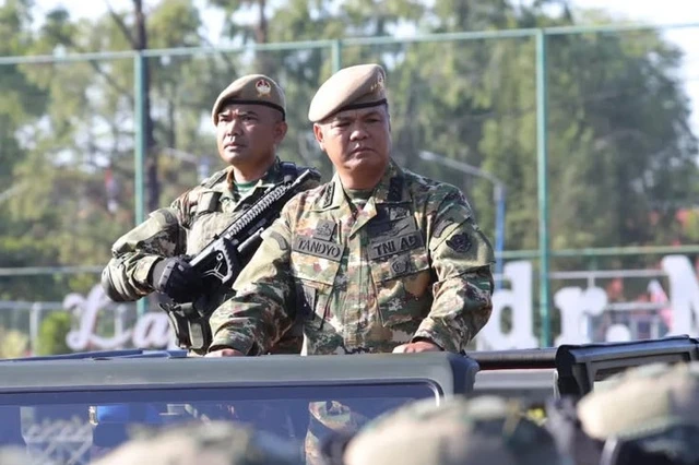 Dua prajurit TNI mengenakan seragam PDL loreng baru dengan baret cokelat, salah satunya berdiri di atas kendaraan dinas militer saat kegiatan apel.