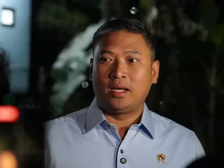 Sudaryono, Kepala Badan Gizi Nasional, sedang memberikan pernyataan. Ia mengenakan kemeja biru muda dengan pin logo instansi di kerahnya